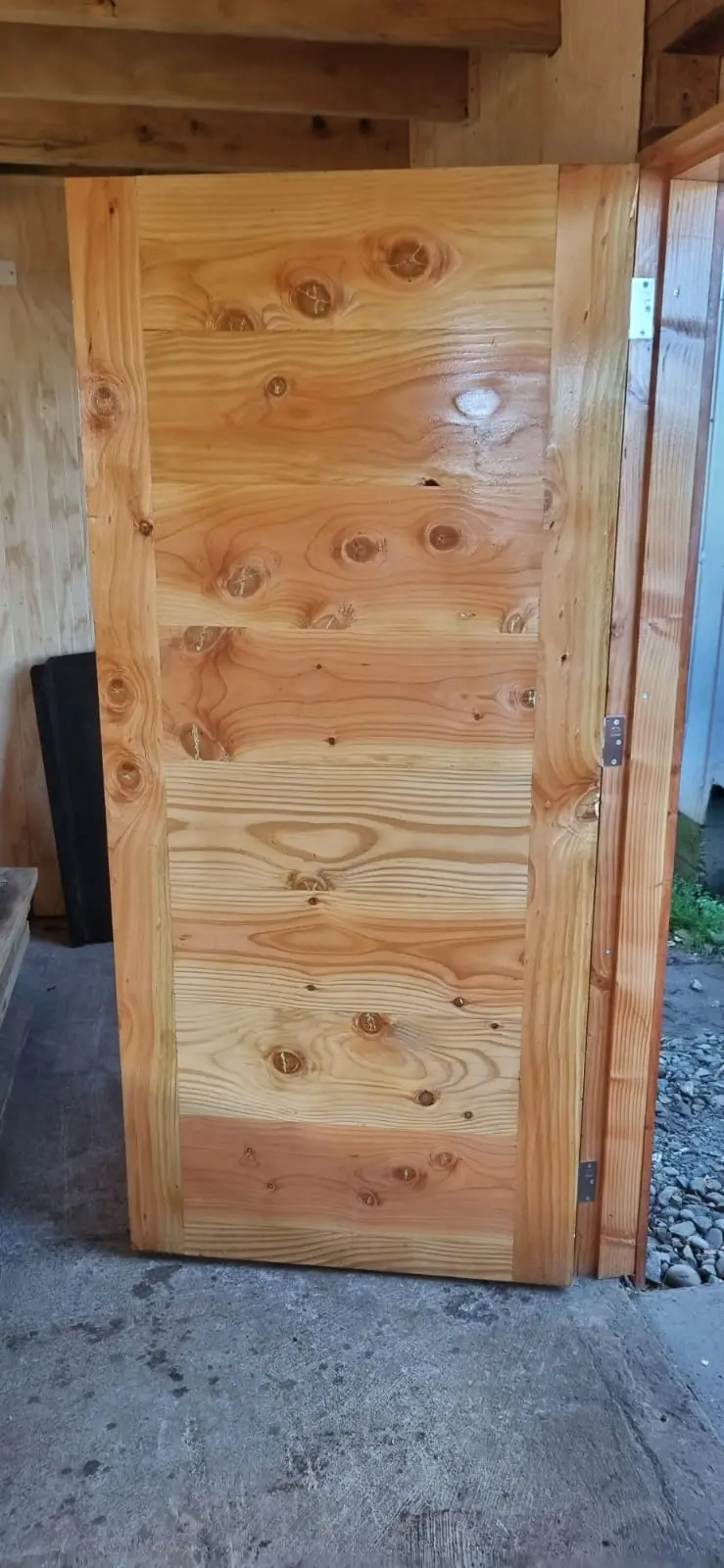 Puerta de madera sólida con barniz brillante y herrajes instalada
