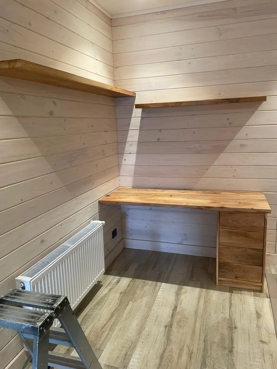 Escritorio a medida con repisas flotantes en madera maciza instalado en pared revestida